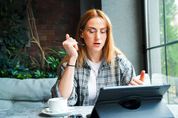 Produktiv sein außerhalb des Büros. Schnappschuss einer attraktiven jungen Geschäftsfrau, die an ihrem Tablet arbeitet, während sie in einem Café sitzt. - Foto, Bild