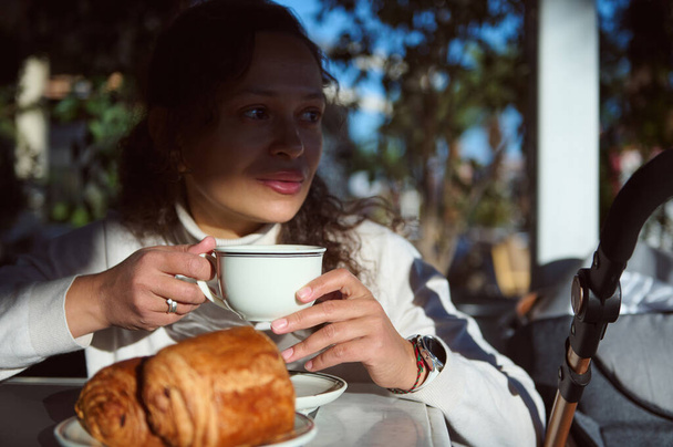アウトドアストリートカフェで朝食を取って,新鮮なエスプレッソコーヒーを飲み,美味しい焼きたてのフランスのカリキュラムを食べる美しいペンギンの若い女性の自信の肖像画 - 写真・画像