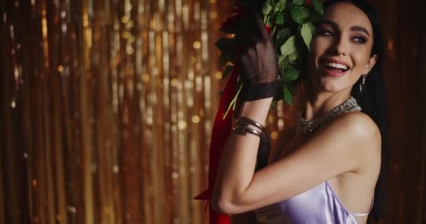 ストリーマーの装飾に対して立っている赤いバラの束を保持する幸せな魅力的な若い女性 - 映像、動画