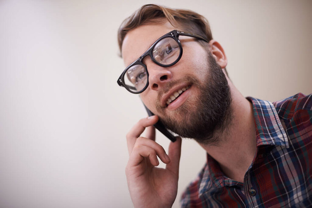 Young man, face and phone call with glasses for conversation, communication or networking at home. Happy male person or freelancer with smile and mobile smartphone for friendly discussion on mockup. - Photo, Image