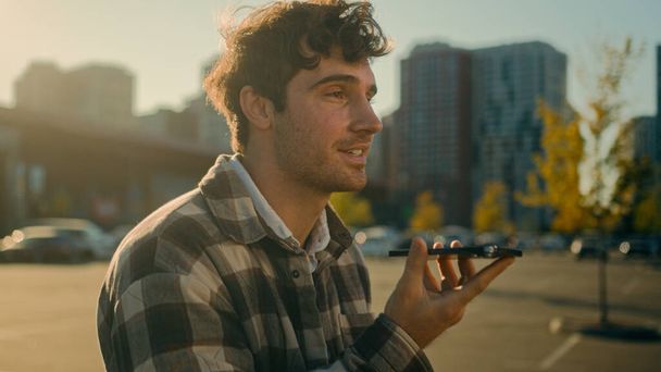 Kaukázusi férfi sétál kívül felvétel hangposta hangposta kihangosító jóképű fickó használ virtuális asszisztens app okostelefon felvétel audio üzenet a városban mosolygós férfi chat barátaival mobiltelefon hírnök - Fotó, kép