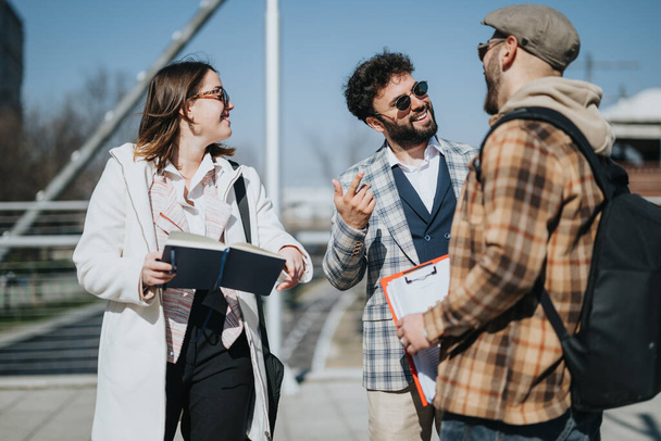 Drei junge Berufstätige nehmen an einem Geschäftstreffen im Freien teil und diskutieren Strategien und Verkäufe in einem Innenstadtbereich. - Foto, Bild