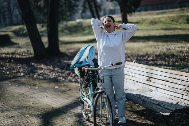 Femme joyeuse profitant d'une pause par une journée ensoleillée avec son vélo vintage dans un parc. - Photo, image
