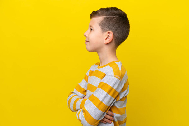 Маленький білий хлопчик ізольований на жовтому тлі в боковому положенні - Фото, зображення
