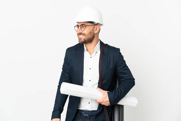 Architekt Mann mit Helm und hält Baupläne isoliert auf weißem Hintergrund aussehende Seite - Foto, Bild