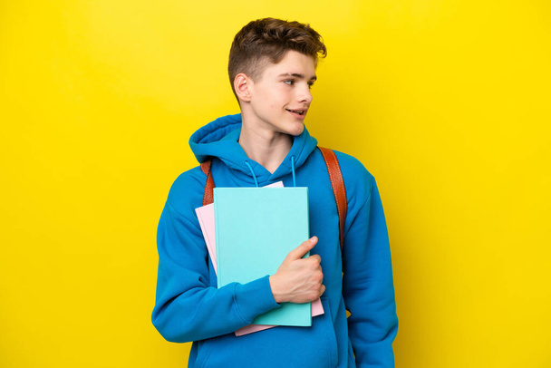 Teenager Russian student man isolated on yellow background looking side - Photo, image