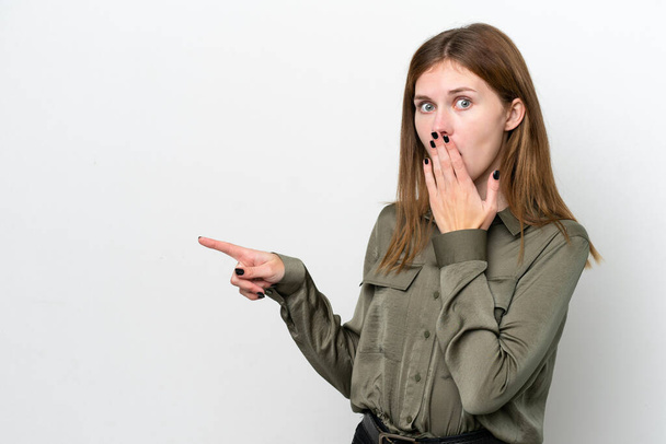 Fiatal angol nő elszigetelt fehér háttér meglepetés kifejezés, miközben rámutatott oldalán - Fotó, kép