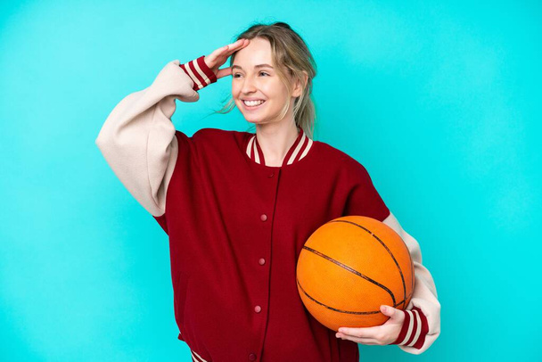 молода баскетболістка біла жінка ізольована на синьому фоні, багато посміхаючись - Фото, зображення