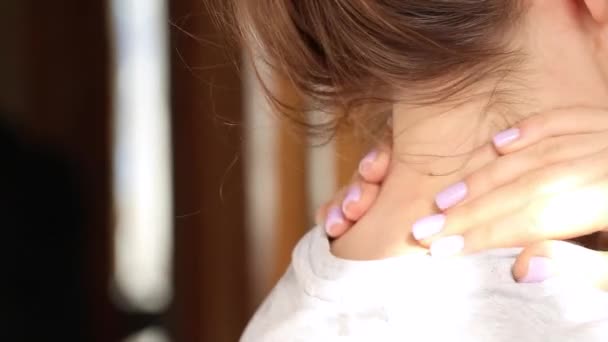 Meisje houdt haar handen achter haar nek thuis, moe, nekpijn, acute pijn in de nek, nekmassage - Video