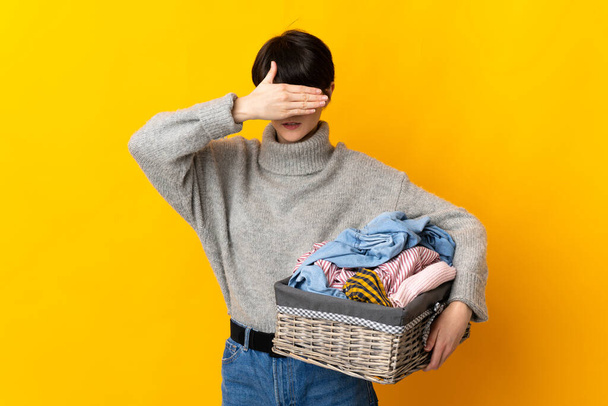 Woman with short hair holding a clothes basket covering eyes by hands. Do not want to see something - Photo, Image