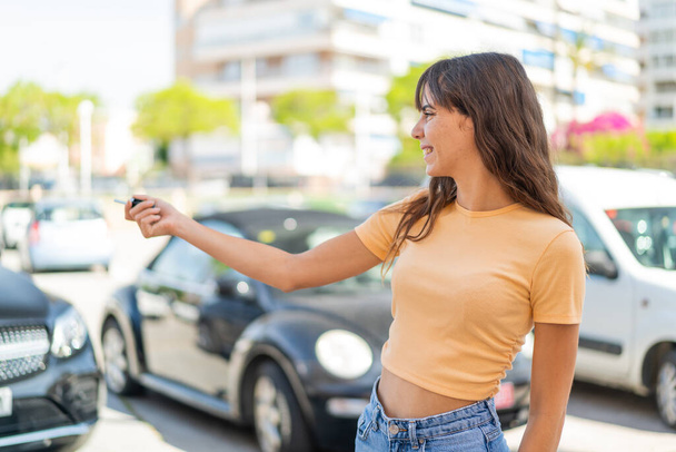 Jeune femme à l'extérieur tenant des clés de voiture - Photo, image