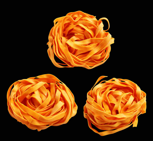 オレンジ イタリアのタグリタテルまたはフェッカチン パスタ古典的なスタック,クリッピング パスと隔離された巣の卵 イタリアのパスタ,黒い背景の影,調理の原料 - 写真・画像