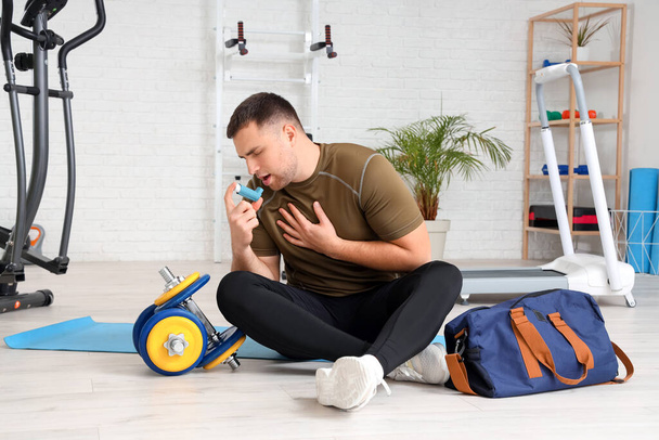 Sportlicher junger Mann mit Inhalator im Fitnessstudio - Foto, Bild