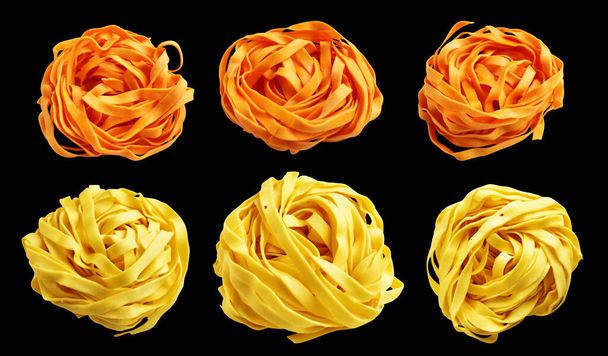 Žluté a oranžové italské tagliatelle nebo Fettuccine těstoviny klasické stack, hnízdo vejce italské těstoviny izolované s výstřižkem cesta, žádný stín v černém pozadí, vaření ingredience - Fotografie, Obrázek