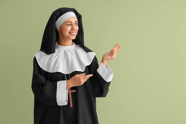 Junge Nonne zeigt etwas auf grünem Hintergrund - Foto, Bild
