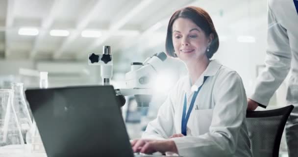 Women, partner and scientist in laboratory with laptop, microscope and check results with ideas for innovation. People, teamwork and point for science, studying and data analysis for pharma research. - Footage, Video