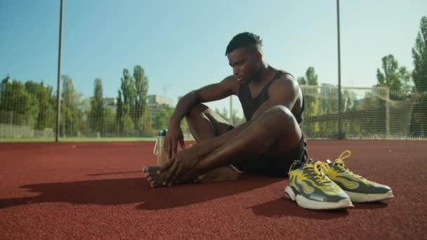 Afrikkalainen amerikkalainen mies tuntuu särky kivulias jalka kipu loukkaantunut jalka harjoituksen jälkeen ulkona mies jalkapalloilija kaveri kärsii vamman luun sormen kallus terveysongelma trauma onnettomuus kaupungin urheilukentällä - Materiaali, video