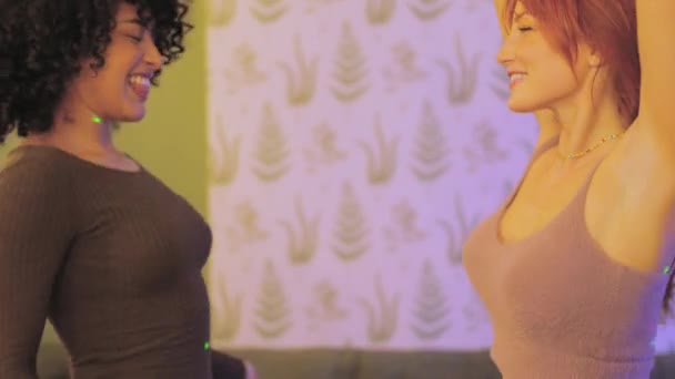 Hidasliikkeinen video, jossa on sivukuva latinalaisamerikkalaisista ja valkoihoisista naisista, jotka tanssivat aistillisia yöjuhlissa kotona - Materiaali, video