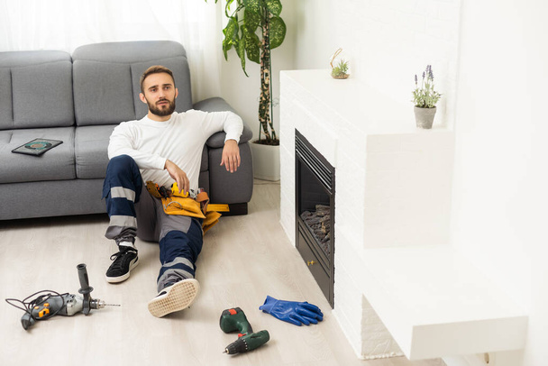 Professional technician with screwdriver installing electric fireplace in room. - 写真・画像
