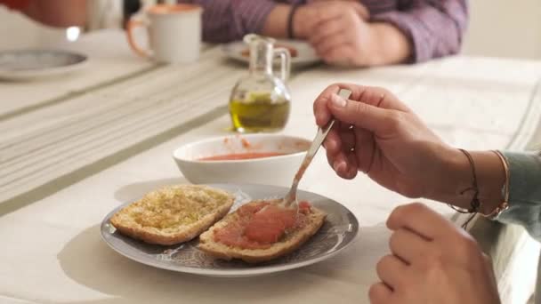 Masaya oturmuş ekmeğe domates döken tanınmamış bir insanın ellerini videoya çek. - Video, Çekim