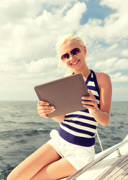 smiling woman sitting on yacht with tablet pc - 写真・画像
