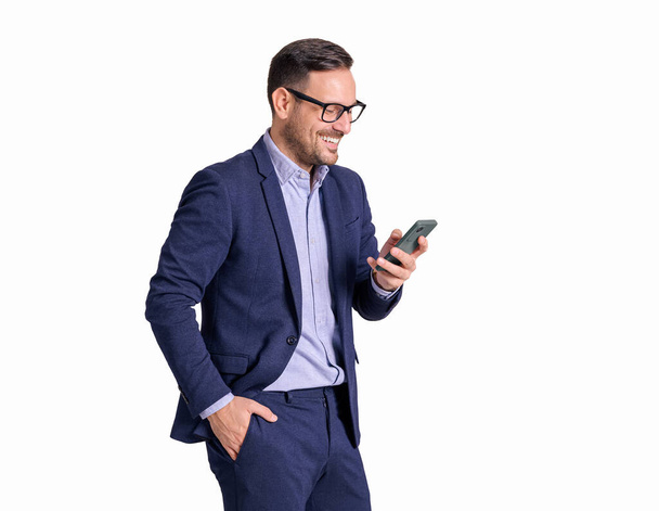 Retrato de homem profissional em óculos sorrindo e mensagens de texto sobre telefone celular no fundo branco - Foto, Imagem