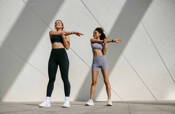Спортивні жінки роблять вправи вранці перед тренуванням на вулиці. Здорова фізична підготовка - Фото, зображення
