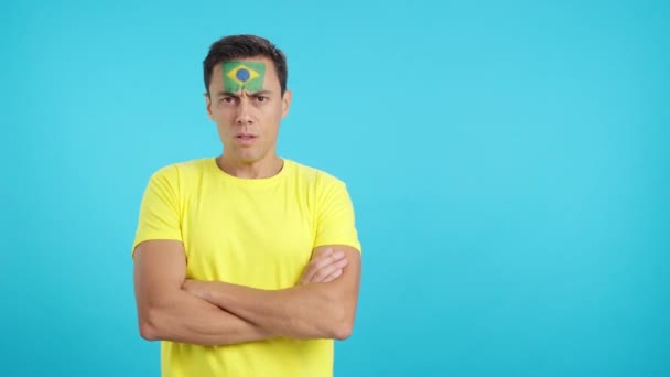 Video en estudio con croma de un hombre digno y serio con bandera brasileña pintado en la cara mirando a la cámara con dignidad - Metraje, vídeo