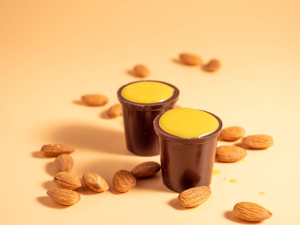 Vanillepudding in een glas chocolade op een oranje achtergrond. Chocolade met vanillepudding en noten. - Foto, afbeelding