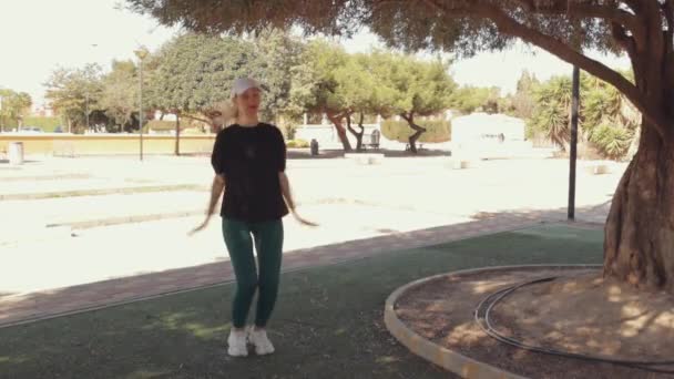 Фітнес-дівчина виконує вправи для ніг, тренує м'язи стегна та коліна та відпочиває на свіжому повітрі. Струнка атлетична жінка в 30 років виконує вправи на відкритому повітрі. Фітнес тренування в природі. Високий - Кадри, відео