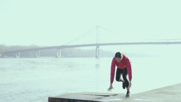 νεαρή γυναίκα κάνει άσκηση κοντά στο ποτάμι - Πλάνα, βίντεο