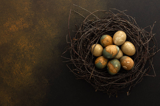 Космические пасхальные яйца в гнезде на коричневом фоне, вид сверху, пространство для копирования - Фото, изображение