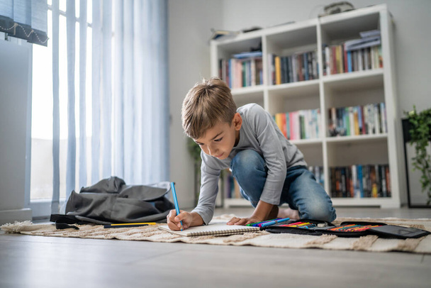 a schoolboy Small caucasian boy play at home draw on the floor doing homework childhood development growing up and education concept copy space domestic life - Photo, Image