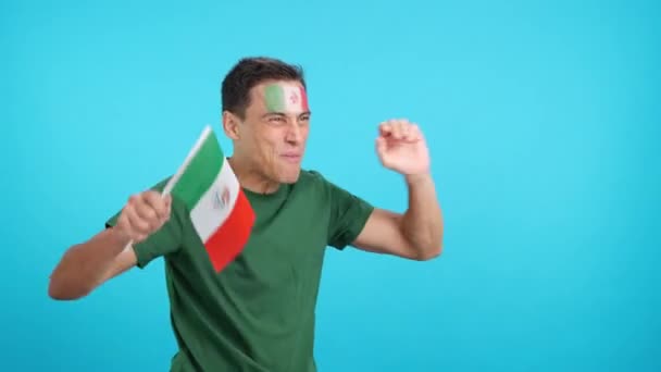 Video in studio met chroma van een man die schreeuwt voor Mexico en zwaait met een nationale vlag, wegkijkend naar de kopieerruimte in het niets - Video