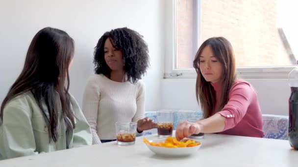 Egy nő fűszeres harapnivalót eszik, miközben a barátai nevetnek a reakcióján egy könnyed pillanatban..  - Felvétel, videó