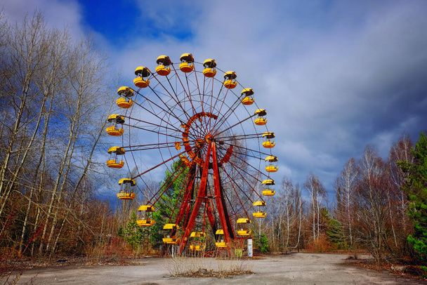 На изображении неиспользованное ржавое колесо обозрения с желтыми каютами. - Фото, изображение