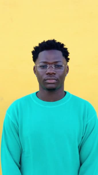 Vertikales Porträt des jungen schwarzen Millennials. Nahaufnahme eines afrikanischen Jungen, der vor gelbem Hintergrund steht. - Filmmaterial, Video