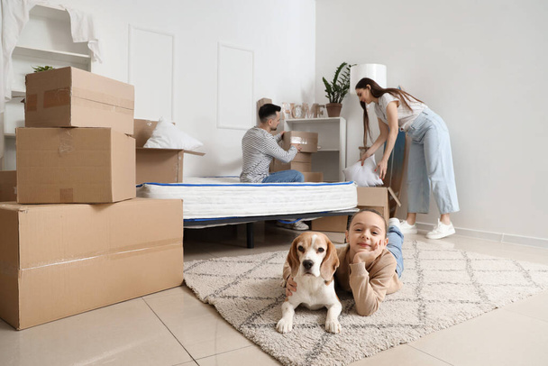 Klein meisje met hond en ouders in de slaapkamer op verhuisdag - Foto, afbeelding