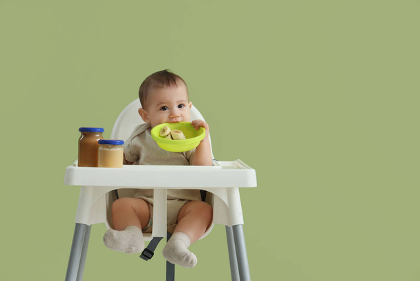 Bebé bonito com tigela de banana na mesa de alimentação em fundo verde - Foto, Imagem