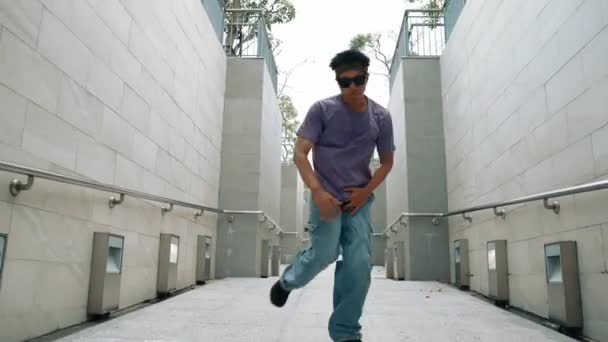 Professionele breakdanser voert straatdans uit op smalle gang. Bekwame Aziatische hipster die op muziek overstapt terwijl B-boy op een smalle muur stapt. Moderne levensstijl. Outdoor sport 2024. Schitterend.. - Video