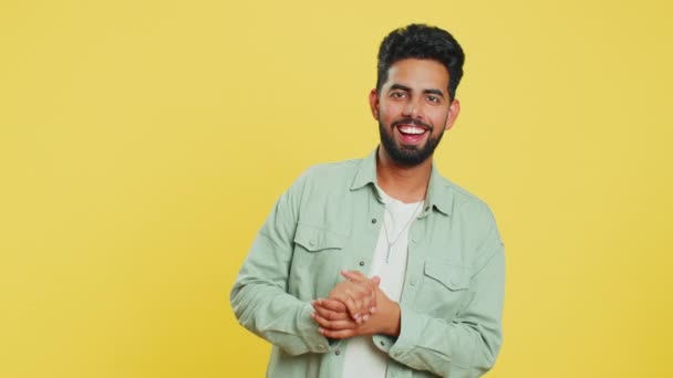 Happy Indian young man laughing out loud after hearing ridiculous anecdote, reaction on funny joke, feeling carefree amused. Positive people lifestyle. Arabian guy isolated on studio yellow background - Footage, Video
