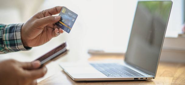 クローズアップマン手 オンラインショッピングを使用してクレジットカードを保持する ラップトップ, 自宅やオフィスでのオンライン決済, インターネットバンキング, 製品を注文するための支出や起業家のための将来のライフスタイルのアイデア - 写真・画像