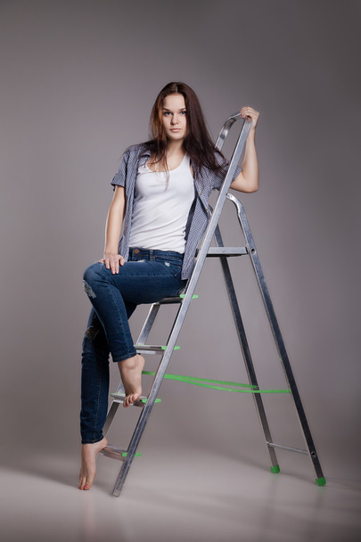 Young woman on step ladder. - Foto, afbeelding