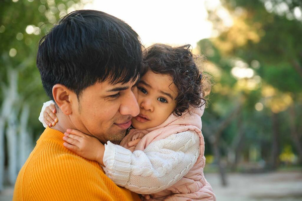 Retrato da feliz filha equatoriana de um ano abraçando seu pai em um parque. - Foto, Imagem