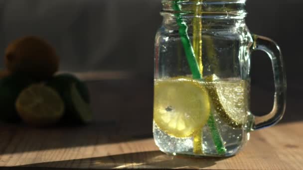 Limón y lima sabor agua gaseosa servida en frasco de vidrio beber primer plano zoom tiro cámara lenta enfoque selectivo - Imágenes, Vídeo