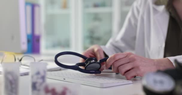 Arzt legt Stethoskop auf Computertastatur in Klinik Nahaufnahme 4k Film Zeitlupe. Online-Konzept für Fernmedizin - Filmmaterial, Video
