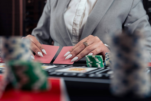 女性はカジノでポーカーをする. 女性はポーカーで遊ぶチップを賭けます. ギャンブルコンセプト - 写真・画像