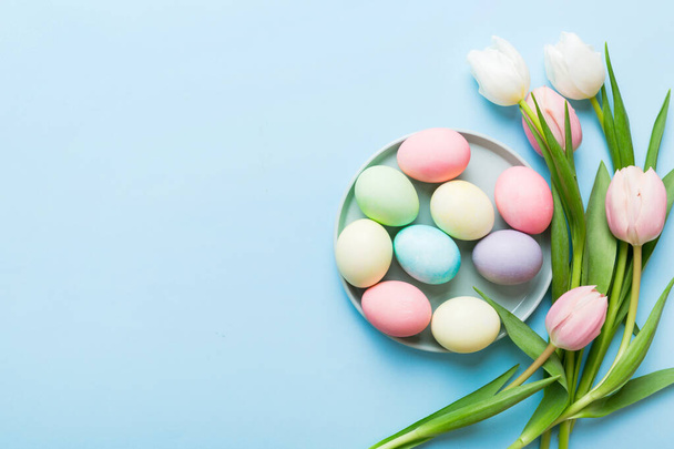 Buona composizione pasquale. Uova di Pasqua in cesto su tavolo colorato con Tulipani gialli. Naturale colorato uova sfondo vista dall'alto con spazio copia. - Foto, immagini
