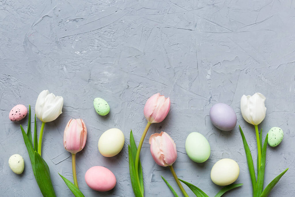 Feliz composición de Pascua. Huevos de Pascua en mesa de colores con tulipanes amarillos. Huevos coloridos teñidos naturales vista superior de fondo con espacio de copia. - Foto, Imagen