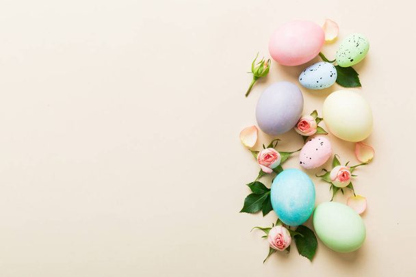 Feliz Pascua. Huevos de Pascua sobre mesa de colores con rosas amarillas. Huevos coloridos teñidos naturales vista superior de fondo con espacio de copia. - Foto, imagen